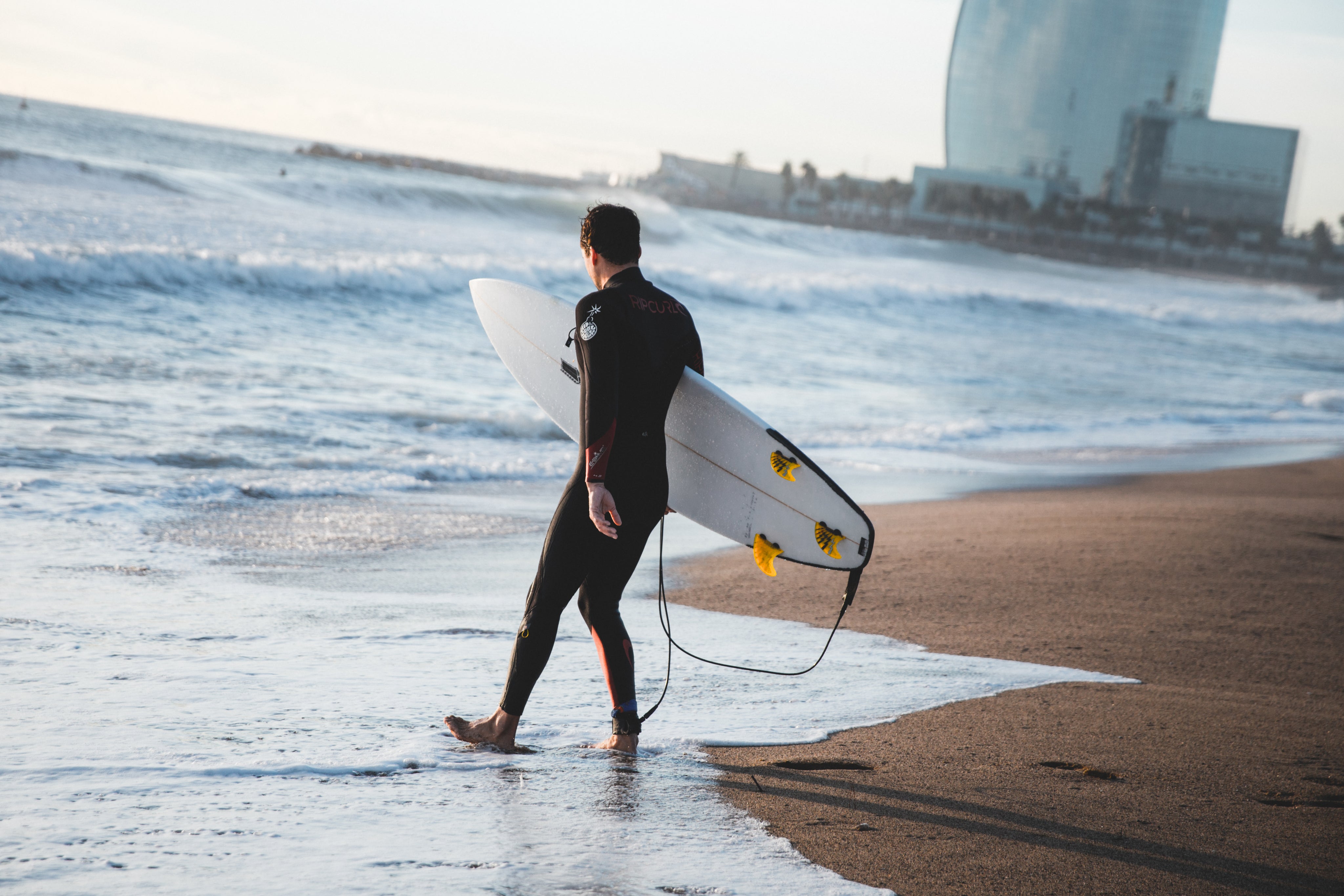 En person er på vej ud på vandet med sit SUP Board fra SURFMORE