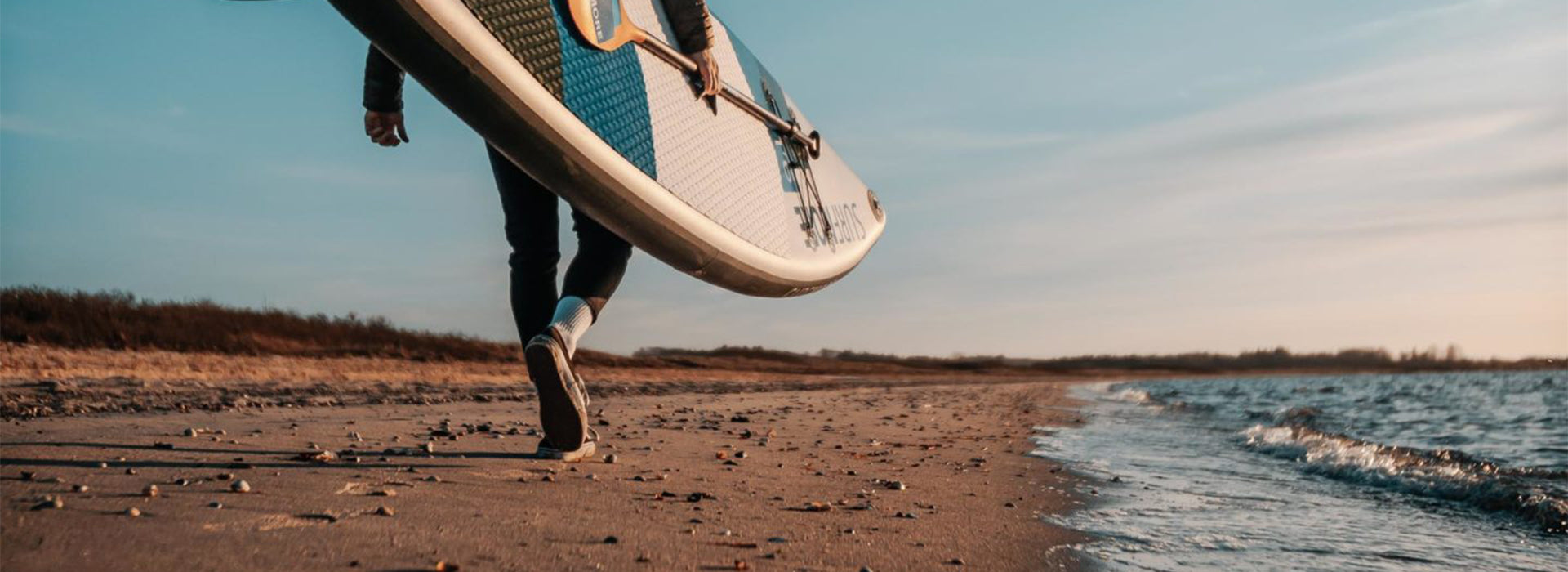 Person bærer på et SUP Board fra SURFMORE
